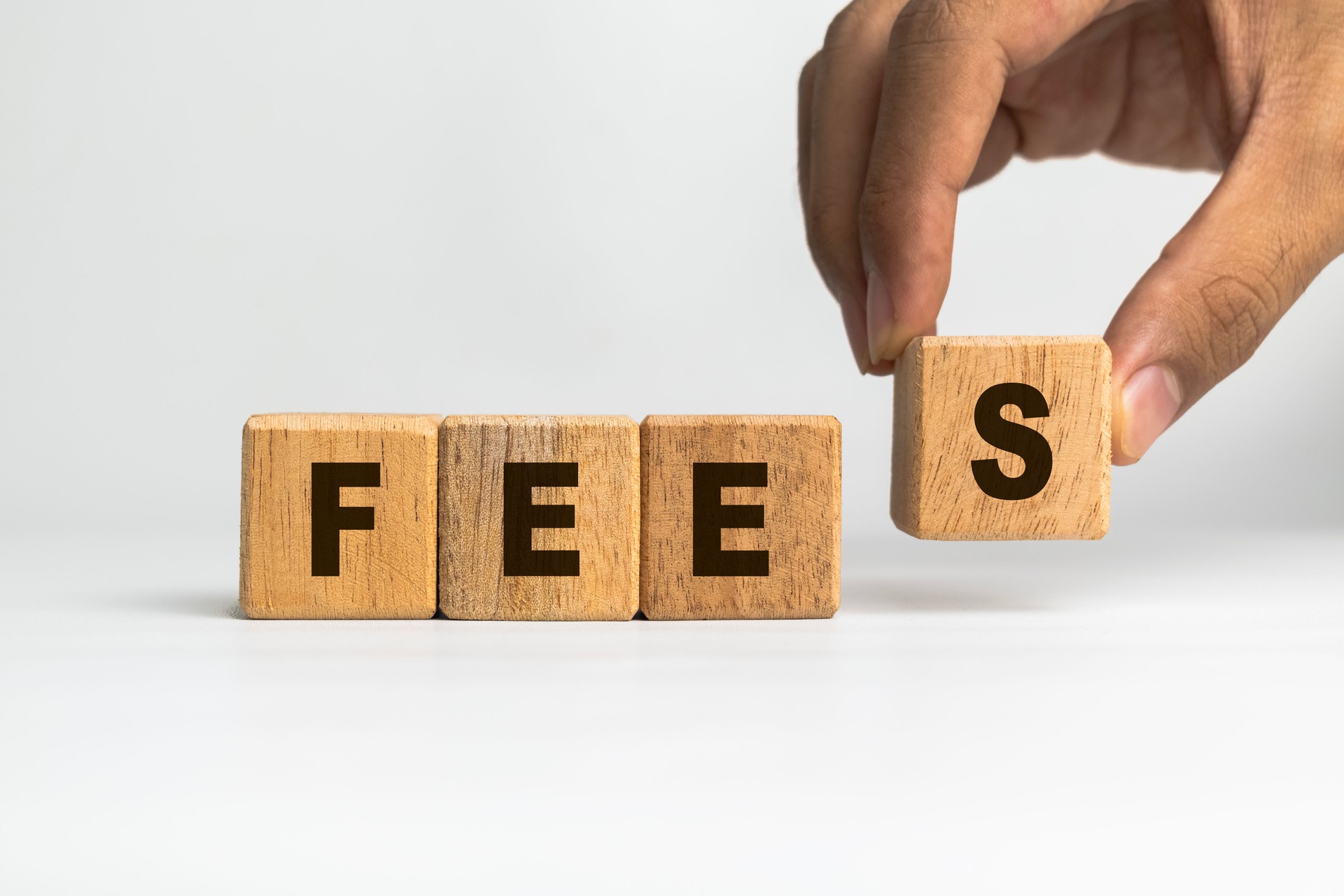 male hand putting wooden blocks with fees words symbol isolated on white background male hand putting wooden blocks with fees words symbol isolated on white background
