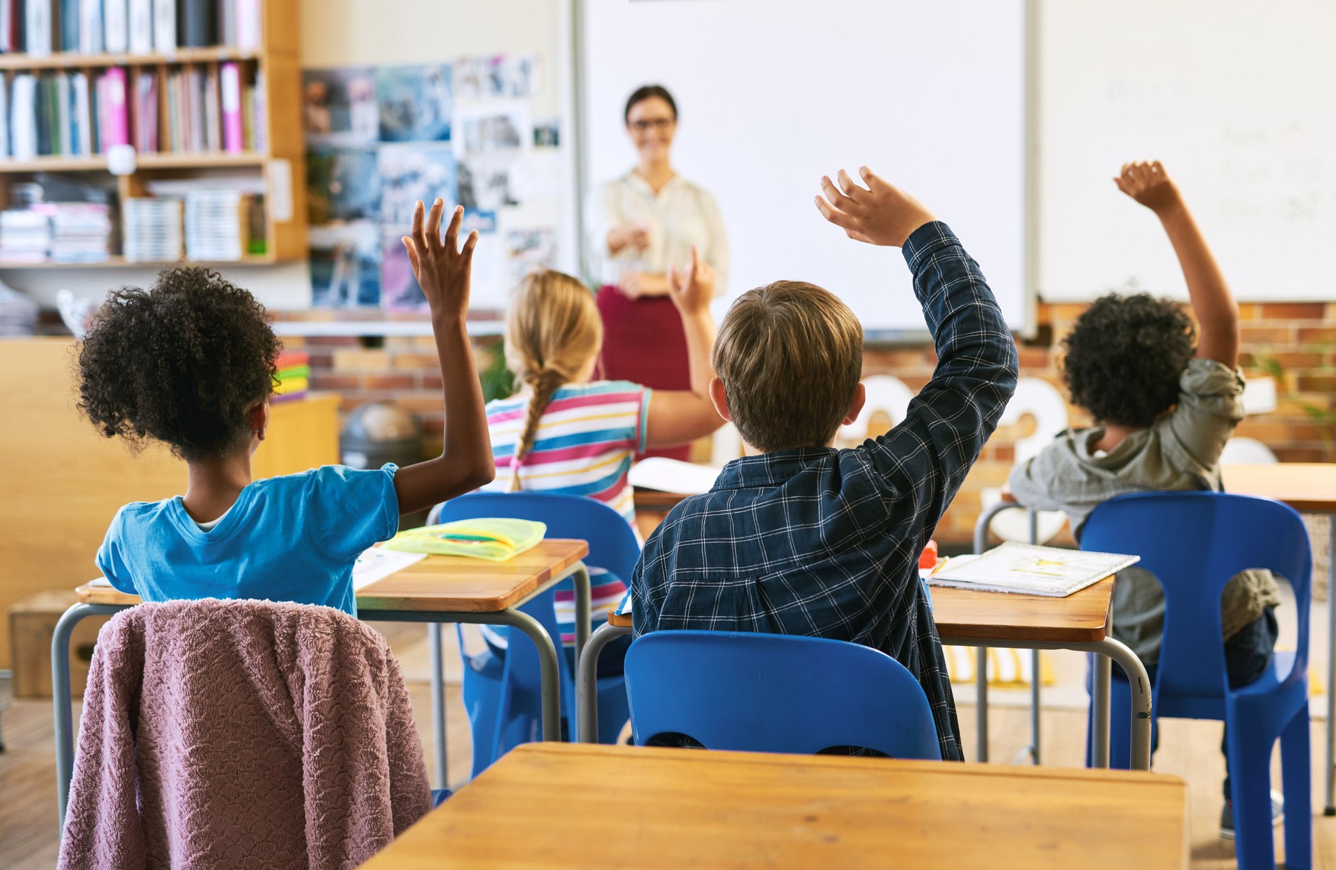 Shot of an unrecognizable group of children sitting in their school classroom and raising their hands to answer a question Shot of an unrecognizable group of children sitting in their school classroom and raising their hands to answer a question